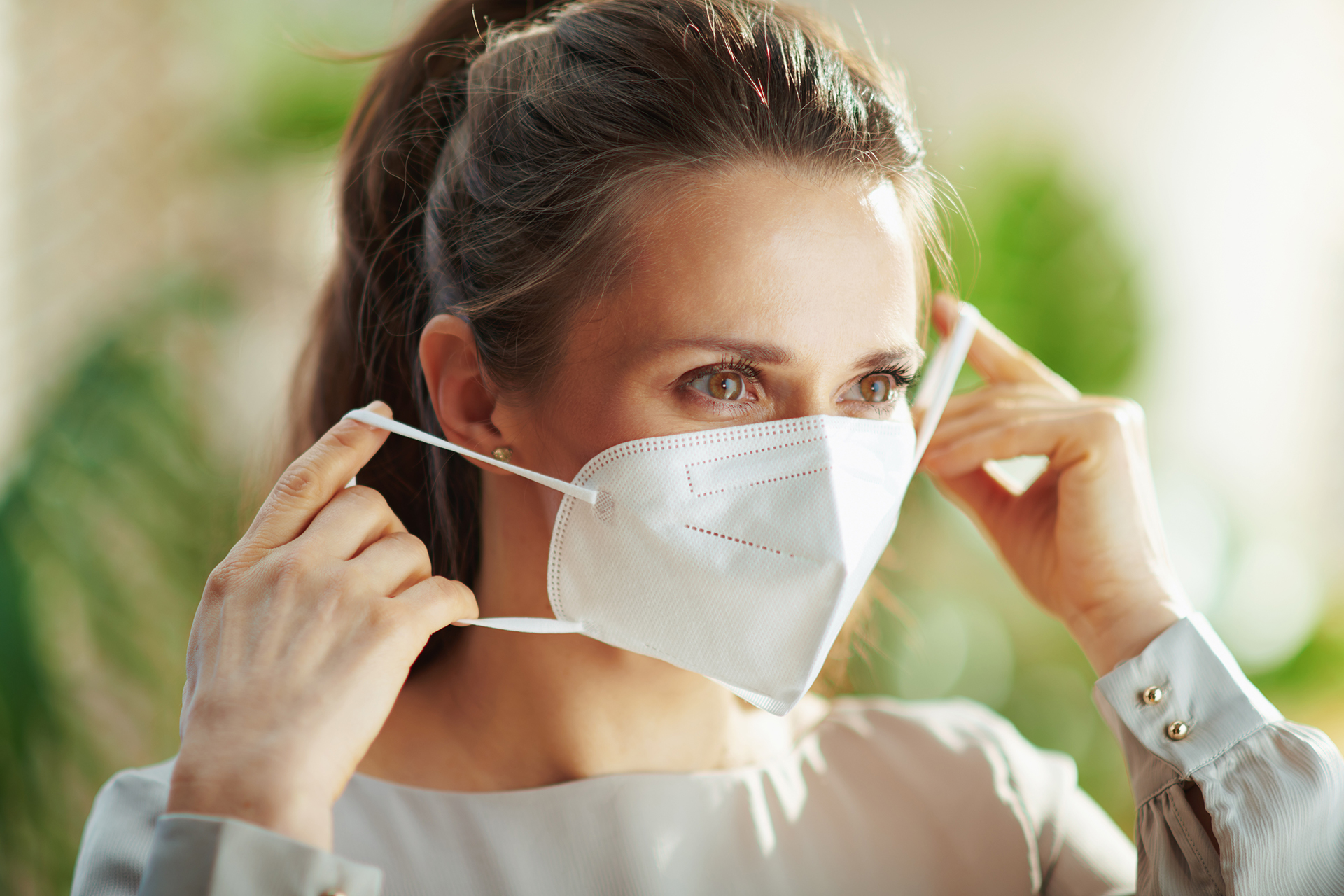 Woman in grey blouse wearing ffp mask